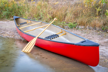 red canoe on a lake shore