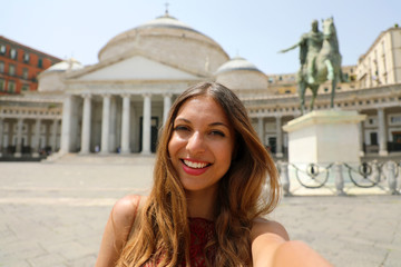 Smiling woman taking selfie photo in Naples with Piazza del Plebiscito square on the background, Naples, Italy