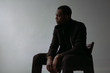 © danilnevsky/Stocksy - Black man in coat sitting on chair