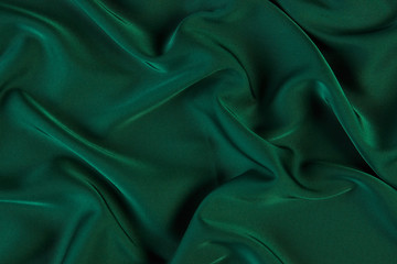 Green silk fabric background, view from above. Smooth elegant green silk or satin luxury cloth texture can use as abstract background with copy space. 