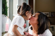 © aremafoto/Stocksy - Asian Mother Kissing Her Daughter at Home