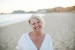 © campbell/Stocksy - Beautiful middle age woman enjoying the beach at sunset
