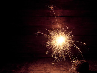 Poster - burning sparkler and christmas lights on wooden background