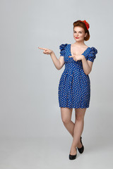 Wall Mural - Body language. Attractive fashionable young woman wearing bright make up and vintage outfit standing isolated in studio, pointing fingers, indicating copyspace wall for your text or advertisement