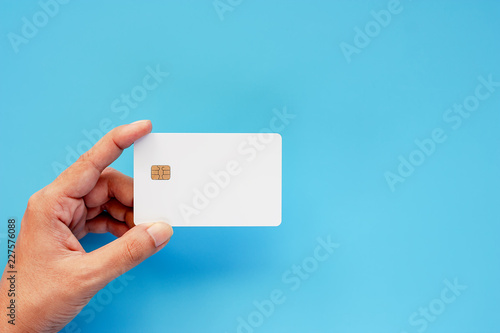 Fotomural Hand holding blank credit chip card on blue background for business and finance