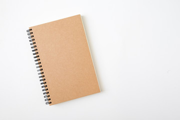 Wall Mural - Top view of closed spiral blank craft paper cover notebook with pencil on white desk background