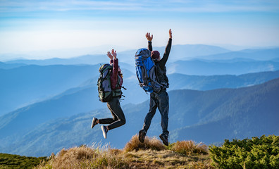 Wall Mural - the man and a woman with backpacks jumping on the mountain