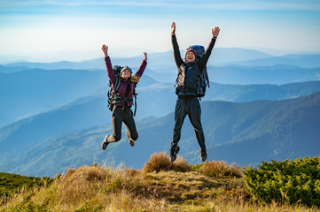 Wall Mural - the man and a woman with backpacks jumping on the mountain