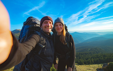 Wall Mural - the happy couple taking a selfie on the mountain background