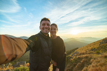 Wall Mural - the smiling couple taking a selfie on the mountain background