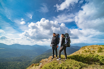 Wall Mural - the young couple on the mountain on the picturesque cloudscape background