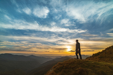 Wall Mural - the man standing on the rock with a picturesque sunset