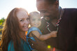 © campbell/Stocksy - Young happy family of three enjoying each other outside on sunny