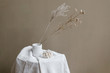 © neekmason/Stocksy - dried flower sprigs in white vase on linen table cloth