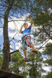 Leisure and activities on nature. Small boy hanging and walking on cables between trees.