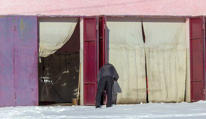 A man opens the gate in the garage in winter