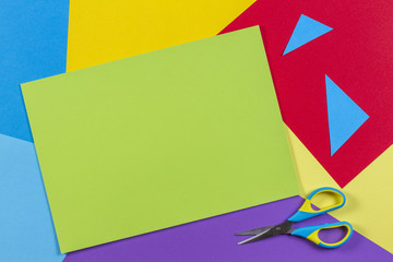 Top view of colored paper with colorful scissors. Kids art and craft paper applique background