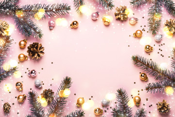 Wall Mural - Pastel Pink Christmas Background. Festive frame of fir branches, toys and golden bokeh lights