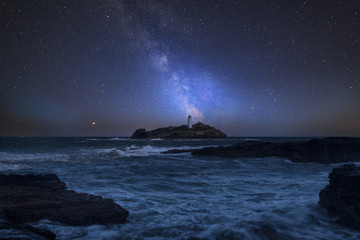 Wall Mural - vibrant milky way composite image over landscape of godrevy lighthouse in corwnall england