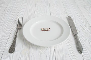 Words on white empty plate from wooden letters: Diet, anorexia and hunger concept. 