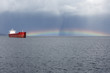 © mikblik/Stocksy - Anchored ship at bay with a rainbow