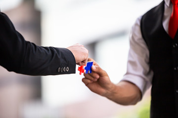 Hands of business people hold paper jigsaw puzzle and solving puzzle together,Business team assembling Jigsaw puzzle,Business group wanting to put pieces of puzzle together.