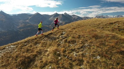 Wall Mural - 4k sport footage, aerial view 44 years old woman and 46 years old man trail running together high up