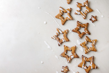 Homemade Christmas star shape sugar caramel cookies with frosting over white marble background. Flat lay, copy space. Sweet xmas or new year gift.