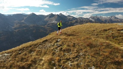 Wall Mural - 4k aerial view man trail running on ridge in mountains