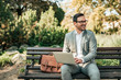 © bnenin - Happy young business man sitting on the bench with laptop.