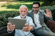 © bnenin - Handsome young and mature men having video call outdoors.