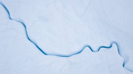 Wall Mural - aerial view from a drone flying over a frozen glacier with a small melt water lake on top. disko bay