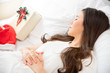 Young Asian woman sleep on the white bed when Christmas day with Santa hat and gift box on the bed