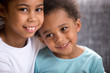 Close up portrait of beautiful adorable black African siblings toddler brother and preschool sister embracing sitting on couch together smiling looking at camera. Closeness of kindered people concept