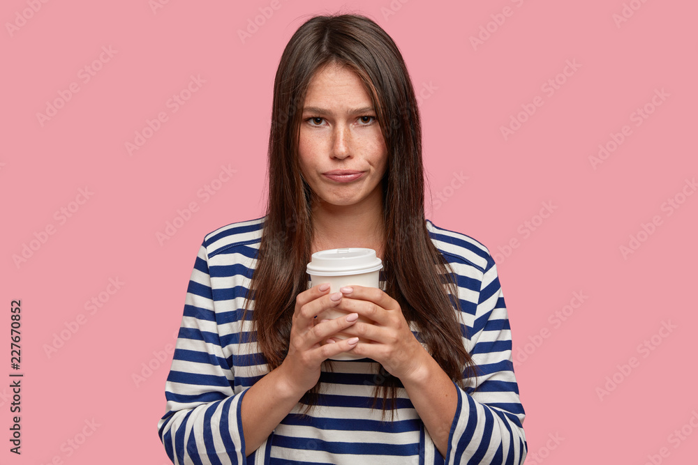 Beautiful young woman has sad miserable expression, holds disposable ...