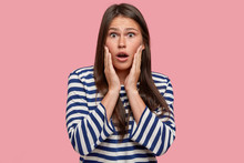 Photo Of Surprised Female Volunteer Shocked With Unexpected Suggestions And Ideas, Hears Amazing Details Of Something, Looks Emotionally, Dressed In Striped Sailor Clothes, Isolated Over Pink Wall