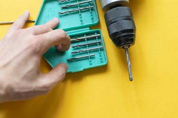 close up hand picking a drill repair tool isolated on yellow background f