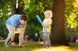 Father and his son playing baseball in park.