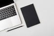 © korkeng - Top view desk with laptop closed black cover notebook and pencil on white desk background