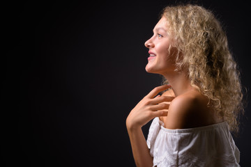 Young beautiful woman with blond curly hair against gray backgro