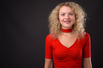 Young beautiful woman with blond curly hair against gray backgro