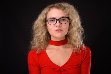 Young beautiful woman with blond curly hair against gray backgro