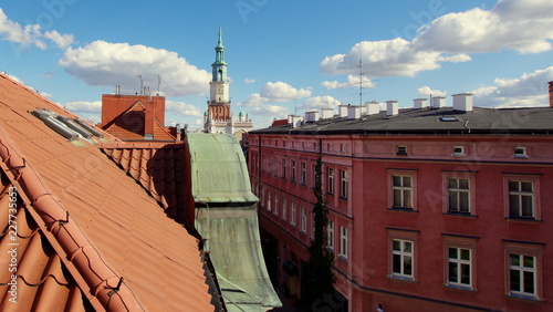 Plakat Ratuszowa wieża na poznańskim rynku widziana z nad dachów starych, czerwonych kamienic starego miasta; wycieczka do Poznania