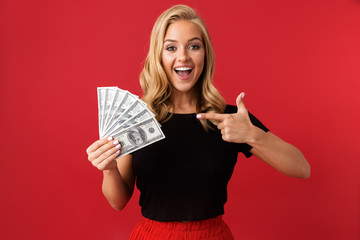 Sticker - Excited woman holding money isolated over red background.