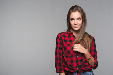 Wall Mural - Young beautiful woman teenager in a red checked shirt and torn denim shorts