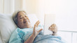 © suphaporn - Elderly patients in hospital bed patients using smart phone call to descendant relatives feel happy ness - medical and healthcare concept