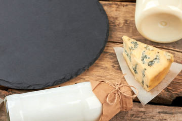 Wall Mural - Dairy products on wooden background. Bottle with milk, sour cream, French roquefort cheese and slate board on rustic wood. Healthy milk food.