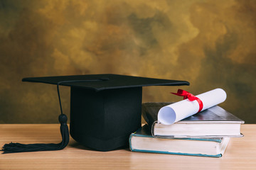 graduation concept.graduation cap,books with degree paper on wood table