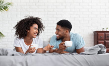 Happy Black Couple Drinking Coffee In Bed