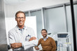 © Yakobchuk Olena - Waist up portrait of smiling medical adviser standing and holding arms crossed with male patient on background